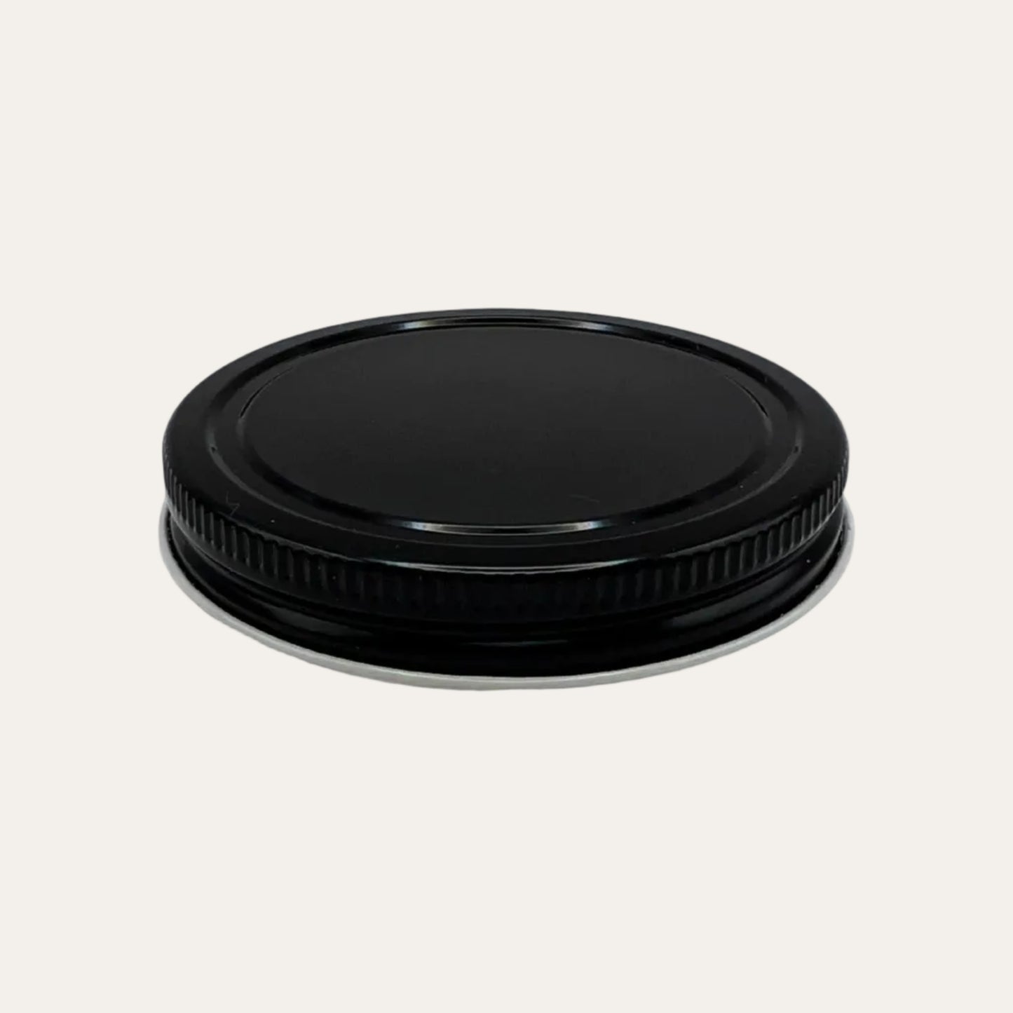 Black metal ribbed lid on cream background.