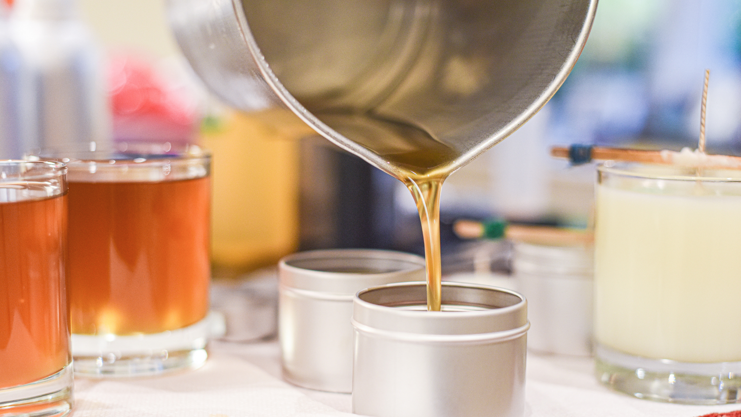soy wax pouring into silver tins with curing candles on each side