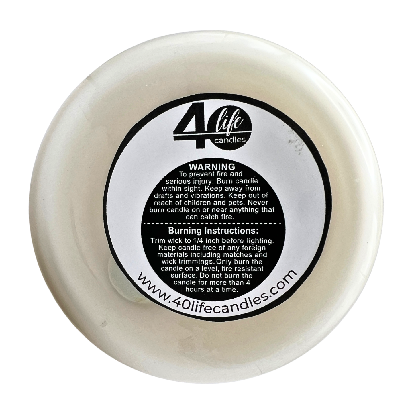 White candle with a black label containing text and a website URL on a white background