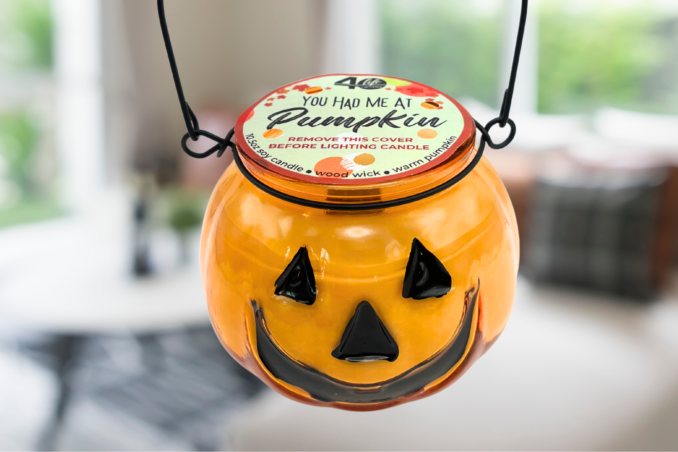 Halloween-themed candle in a pumpkin container with a label on a blurred background