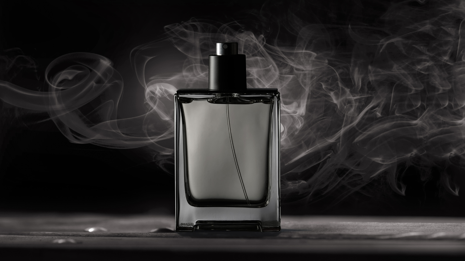 glass cologne bottle with white smoke and black background.