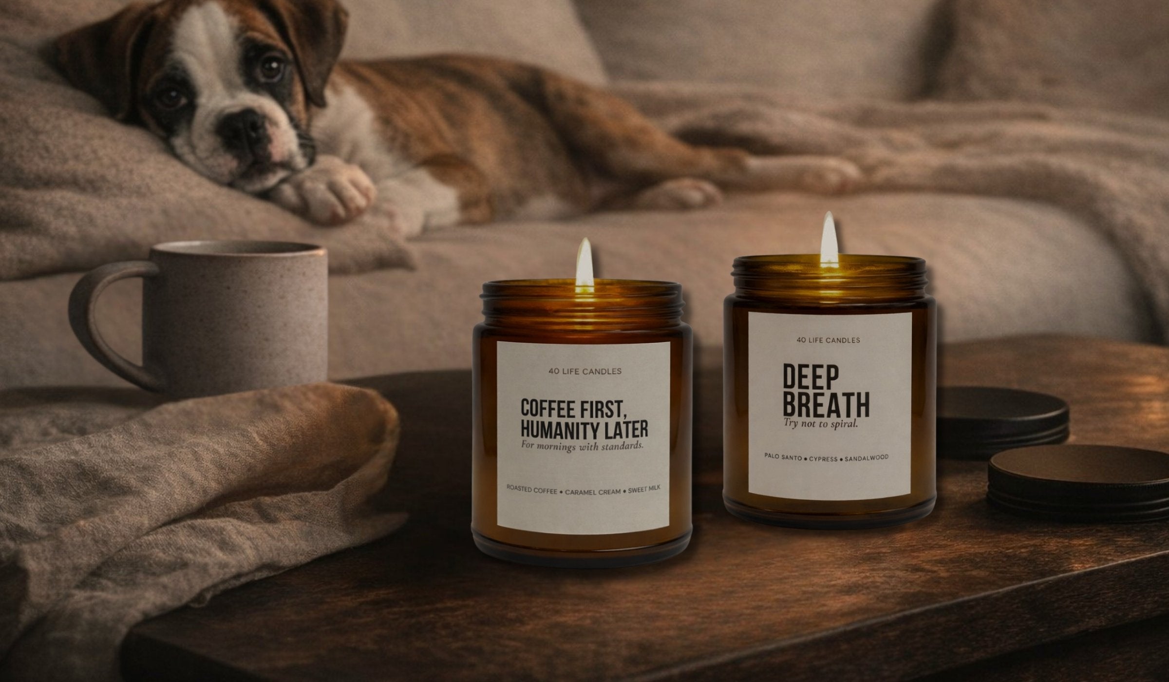 Two candles labeled 'Coffee First Humanity Later' and 'Deep Breath' on a wooden table with a dog in the background.