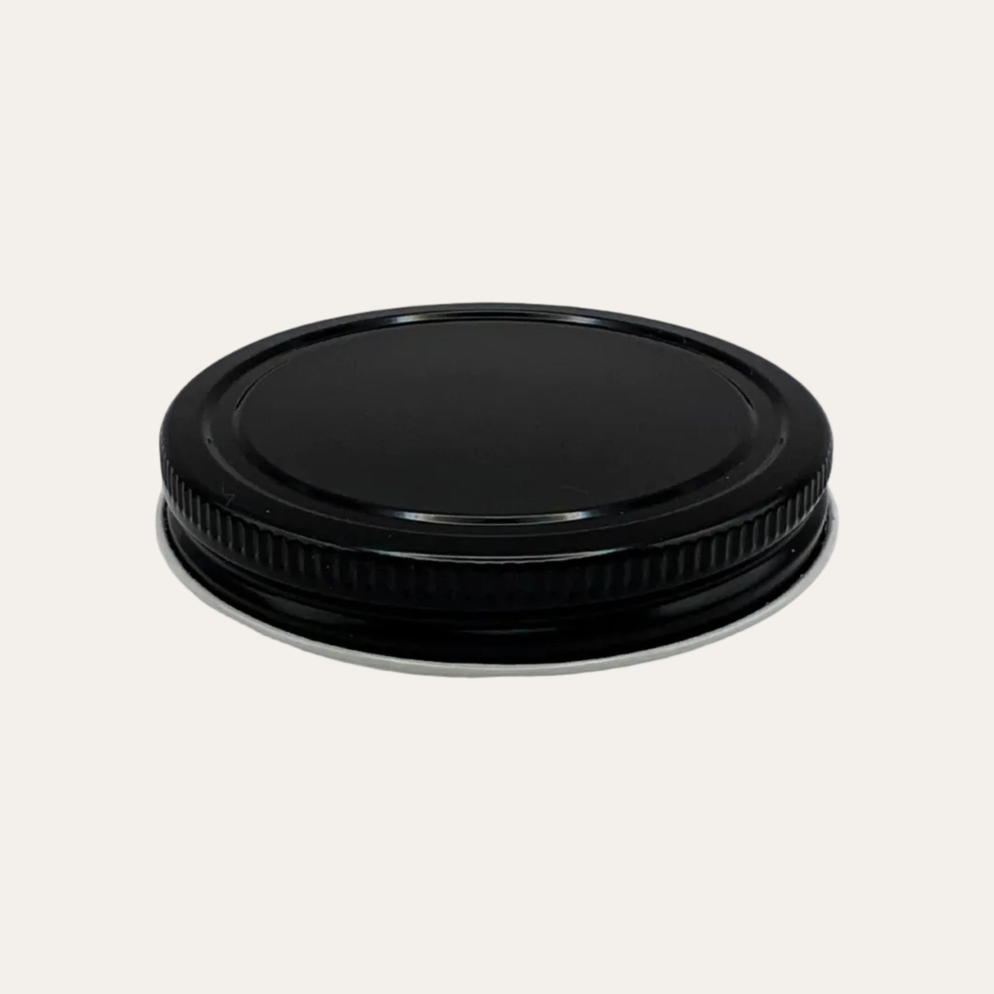 Black metal ribbed lid on cream background.
