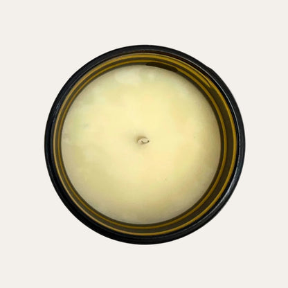 Round candle with a wick and amber container on a cream background