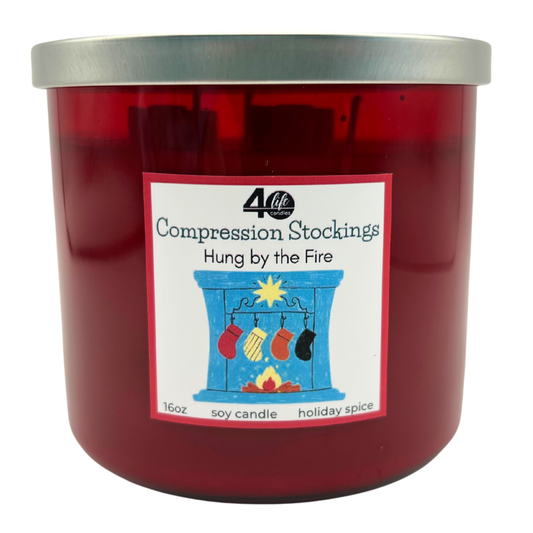 Red candle with a label featuring compression stockings and a fireplace illustration on a white background.