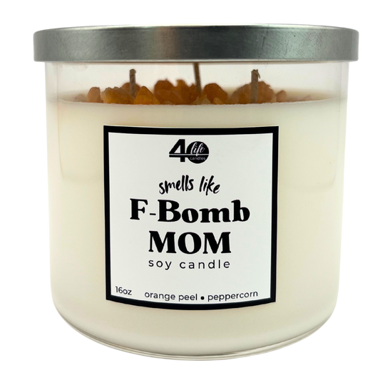Candle with a label reading 'smells like F-Bomb Mom' on a white background
