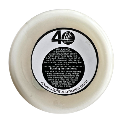 White candle with a black label containing text and a website URL on a white background