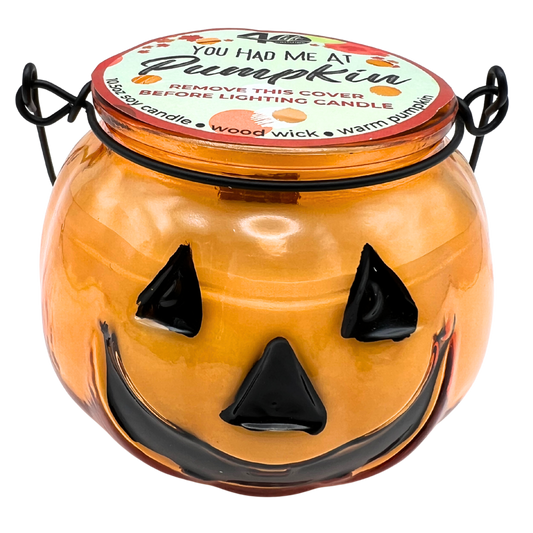 Halloween-themed candle jar with a jack-o'-lantern face on a white background