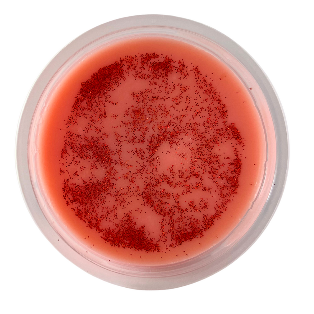 Orange soy wax tart in a 2oz shot cup with orange glitter on top. White background.