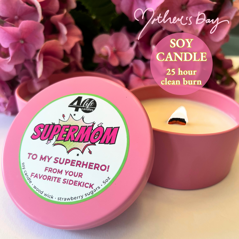 SuperMom soy candle in a soft pink tin with a wood wick and pink flowers in the background.